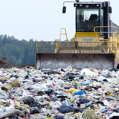 A Landfill Site With A Machine Moving Rubbish