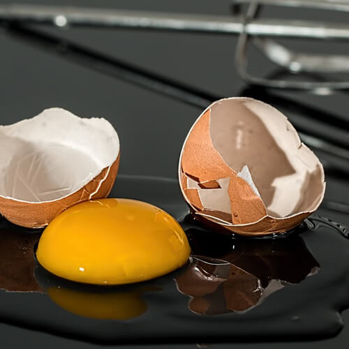 A Cracked Egg With The Yolk Falling Out
