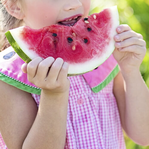 A Child Eating A Slice Of Watermelon