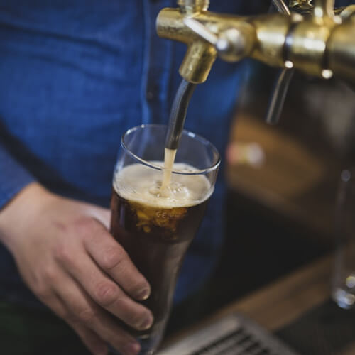 A Person Pouring A Pint Of Beer In A Pub
