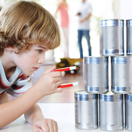 A Child Holding A Magnet Up To Some Tin Cans