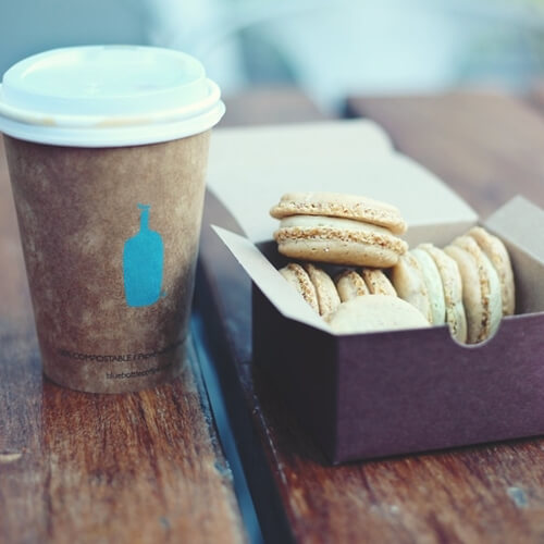 A Disposable Cup Of Coffee With Macarons