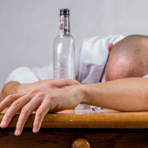 A Man Asleep Next To A Empty Glass Bottle