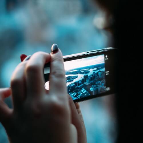 A Person Holding A Phone Taking A Landscape Picture