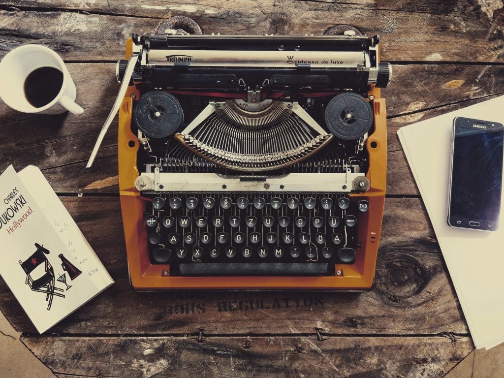 A Typewriter On A Desk With A Mug Of Coffee Next To It