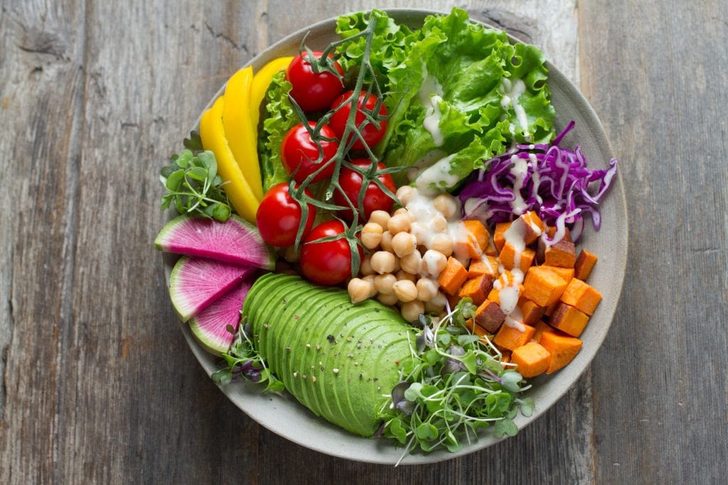 A Bowl Of Salad With Numerous Ingredients Including Avocado, Chickpeas & Sweet Potato