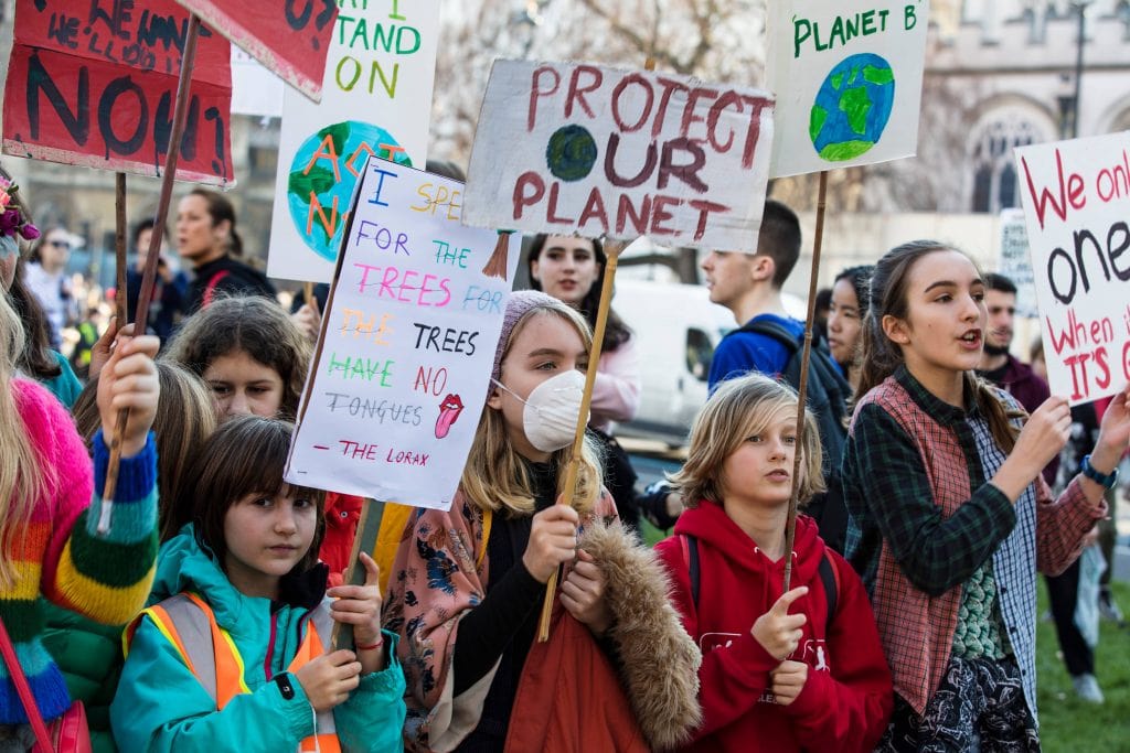 A Environmental Protest With A Group Of People Holding Signs