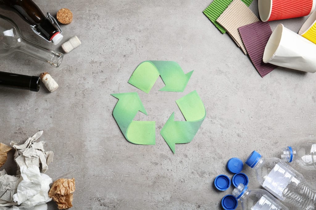 A Recycling Logo With Different Materials Surrounding It