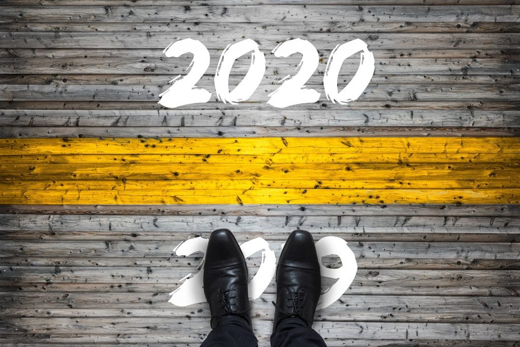 A Pavement With A Person Stood On "2019" Ready To Cross Into "2020"