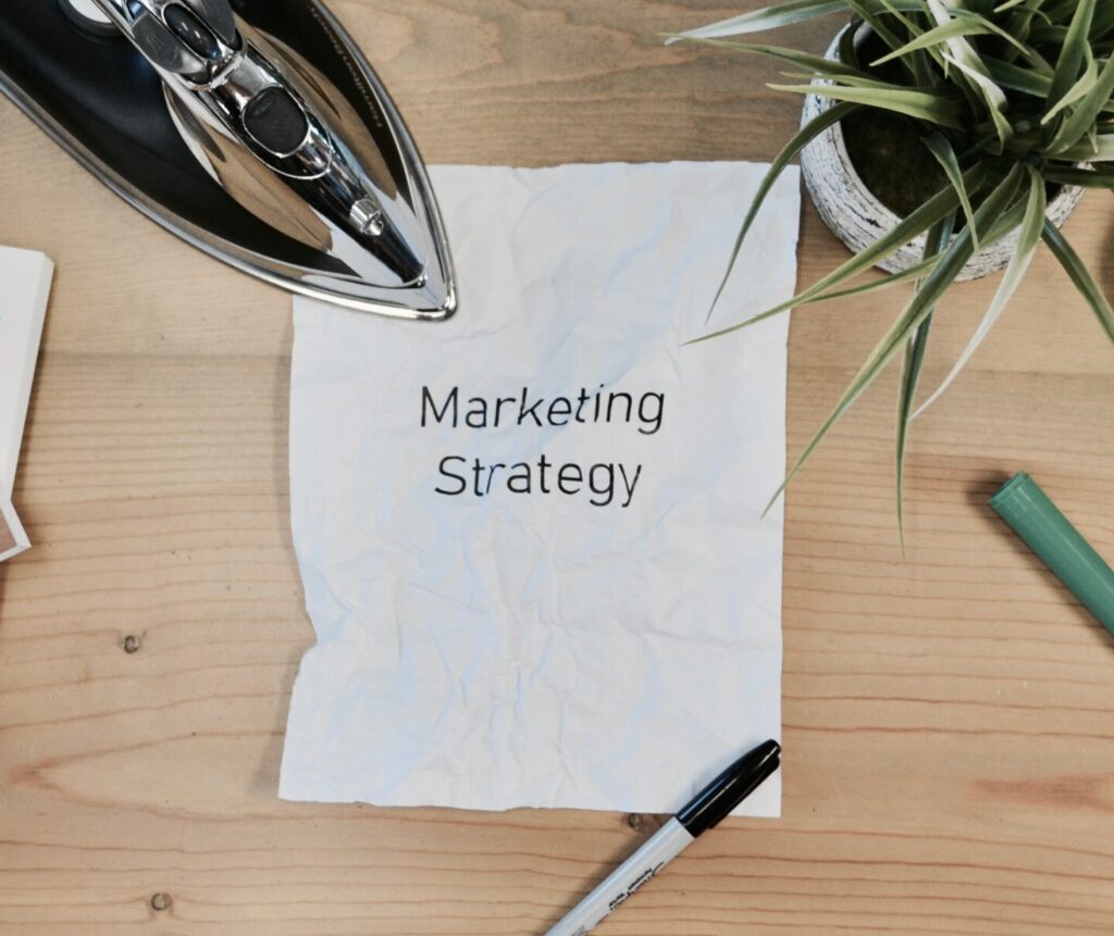 Piece Of Paper On A Desk With "Marketing Strategy" Written On It